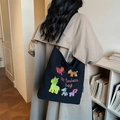 Grande borsa tote in tela nera con ricamo di animali indossata da una modella - Nero