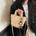 Borsa a secchiello minimalista crema con tracolla regolabile e ciondolo a bambolina - Con Ciondolo / Cachi chiaro