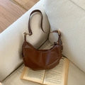 Borsa hobo in pelle marrone minimalista con dettagli a pieghe su un divano a trama - Marrone