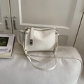 Close-up of cream pillow bag with pleated leather texture and silver rivet details - White