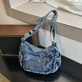 Dettaglio della borsa a tracolla in denim vintage con goffratura floreale e cerniere multiple - Blu