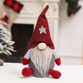 Gnome de Noël en peluche avec bonnet rouge à étoile et barbe blanche sur fond de fête - Rouge