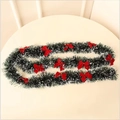 Close-up of green Christmas tinsel with white snow tips and red bows for festive decoration - Dark Green White Tinsel With 12 Red Bows