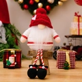 Weihnachtswichtel mit Herzmütze und langen hängenden Beinen auf einem Holzhocker - Rot