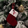 Macro detail of red knitted Christmas stocking with white embroidered letter V on tree - Style V (Red Knit Embroidered V)
