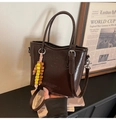 Détail du sac seau en cuir verni marron foncé avec pompon en perles et poignée - Marron