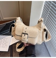 Detail der beigen Motorradtasche aus Kunstleder mit silbernen Schnallen und Nietenverzierung - Cremeweiß