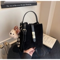 Detail der schwarzen matten Eimertasche mit Goldschnalle und süßem Teddybär-Anhänger - Schwarz mit Anhänger