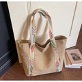 Macro shot of large beige nylon tote bag with floral pattern straps in a cozy home setting - Khaki