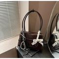 Macro detail of dark brown patent leather shoulder bag with a white lace bow accessory - With Charm / Brown