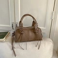 Close-up of matte brown tote bag showing tassel details and lace-up handle design - Tan
