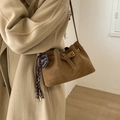 Brown suede bucket shoulder bag with heart pendant and fringe on a model wearing camel coat - Brown