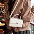 Cream rectangular crossbody bag in faux leather with silver twist lock in a cafe setting - White