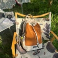 Detalle de mochila de cuadros naranja y beige con cordón en una silla de camping - Con Colgante / Caqui y Naranja