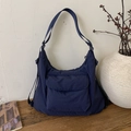 Detail einer dunkelblauen Nylon-Umhängetasche mit Vordertasche auf einer Holzfläche - Dunkelblau
