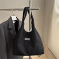 Minimalist black pleated tote bag with fashion tag on a stainless steel hanger - Black