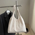 White pleated fabric tote bag with fashion label on a minimalist display stand - White