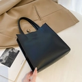 Minimalist black matte leather tote bag with round embossed detail and flat handles - Black