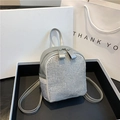 Mini silver backpack with glittering rhinestones and metal zippers on a display tray - Silver