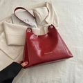 Glänzende dunkelrote Schultertasche aus Ölwachsleder mit Goldlogo und Kettenriemen - Rot