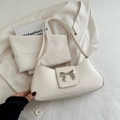 Chic cream white underarm bag with a silver metal bow accent and matching shoulder strap - White