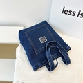 Deep blue denim tote bag with visible yellow stitching and modern front patch pocket - Dark Blue