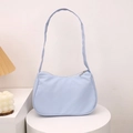 Minimalist light blue crescent underarm bag displayed on a sleek white pedestal - Blue