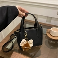 Bolso tipo cubo chic de cuero negro con herrajes dorados y un colgante de monstruo - Con Colgante / Negro