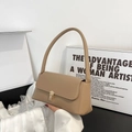 Bolso de hombro baguette caqui minimalista con hebilla de metal dorado en una pose de mano - Caqui