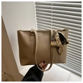 Detail der minimalistischen Tragetasche mit Kontrastnaht und floralem Seidenschal-Accessoire - Khaki