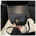 Classic black saddle bag with lychee texture and golden clasp on a gift box - Black