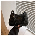 Close-up of black woven leather handbag with gold metal hardware and knotted strap details - Black