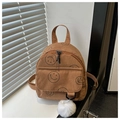 Detailed close-up of brown corduroy backpack with smiley prints and white fur ball - Brown