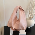 Chic pink tote bag with unique knot handle design on minimalist white book background - Pink