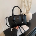 Elegant black leather handbag with white Fashion text and knotted handles on shoulder strap - Black