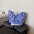Blau-weiß gestreifte Canvas-Tragetasche mit Vordertasche auf einem stilvollen schwarzen Ledersofa - Blau