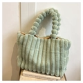 Detail of sage green faux fur tote with plush ball handle and vertical striped texture - Green