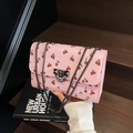 Roze schoudertas met kersenprint en grijze metalen ketting op een houten trap - Roze