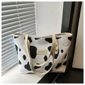 Dettaglio della borsa tote con stampa mucca, manici in pelle beige e logo moda - Stampa mucca