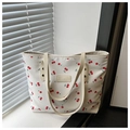Dettaglio della borsa tote bianca con motivi a ciliegie rosse e logo in pelle beige - Ciliegia