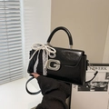 Detail der glänzenden Ledertasche mit Perlenbogen, Spitzenschleife und G-Schnalle - Mit Anhänger / Schwarz