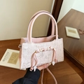 Borsa a tracolla rosa in pizzo con ciondoli di perle e nastri su un tavolo di legno - Rosa