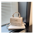 Detail of a beige handbag featuring a metal bow, scalloped edges, and knotted handle texture - Khaki