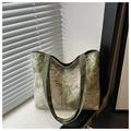 Détail d'un sac cabas en toile avec motif bambou sur un rebord de fenêtre ensoleillé - Vert