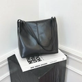 Minimalist black glossy leather shoulder bag with vertical stitching on white display - Black