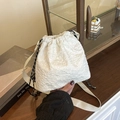 Borsa a secchiello bianca con texture floreale e tracolla larga su un tavolo in legno - Bianco