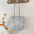 Blaue Tragetasche mit Blumenmuster und grauen Lederriemen an einem Holzhaken - Blau