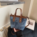 Chic blue denim tote bag with brown leather straps and gold studs on a neutral background - Blue