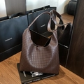 Bolso tote de cuero trenzado marrón oscuro con correa ancha en un escenario de moda lujo - Marrón