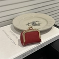 Mini red lychee leather kiss-lock pouch for coins and jewelry on white book - Red